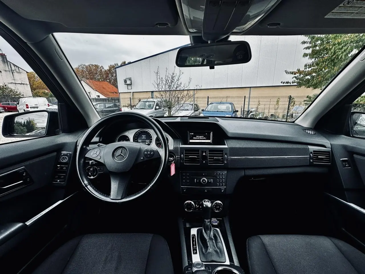 Vue intérieure avant du tableau de bord noir du Mercedes GLK 220 CDI 4-Matic avec volant multifonctions et écran central.