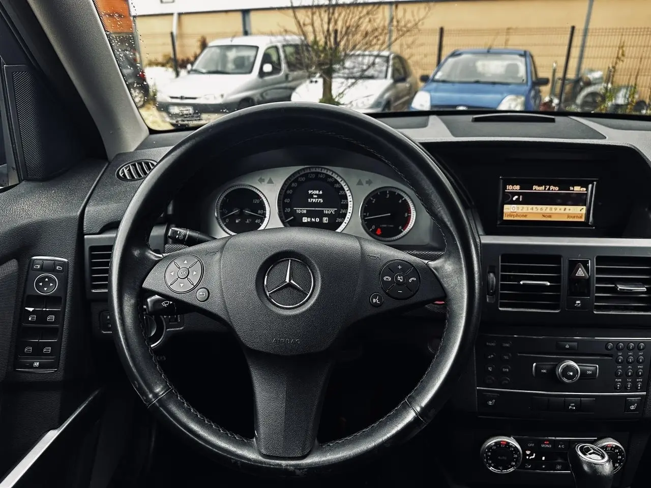 Vue intérieure centrée sur le volant cuir Mercedes GLK 220 CDI 2010 avec tableau de bord et écran multimédia.