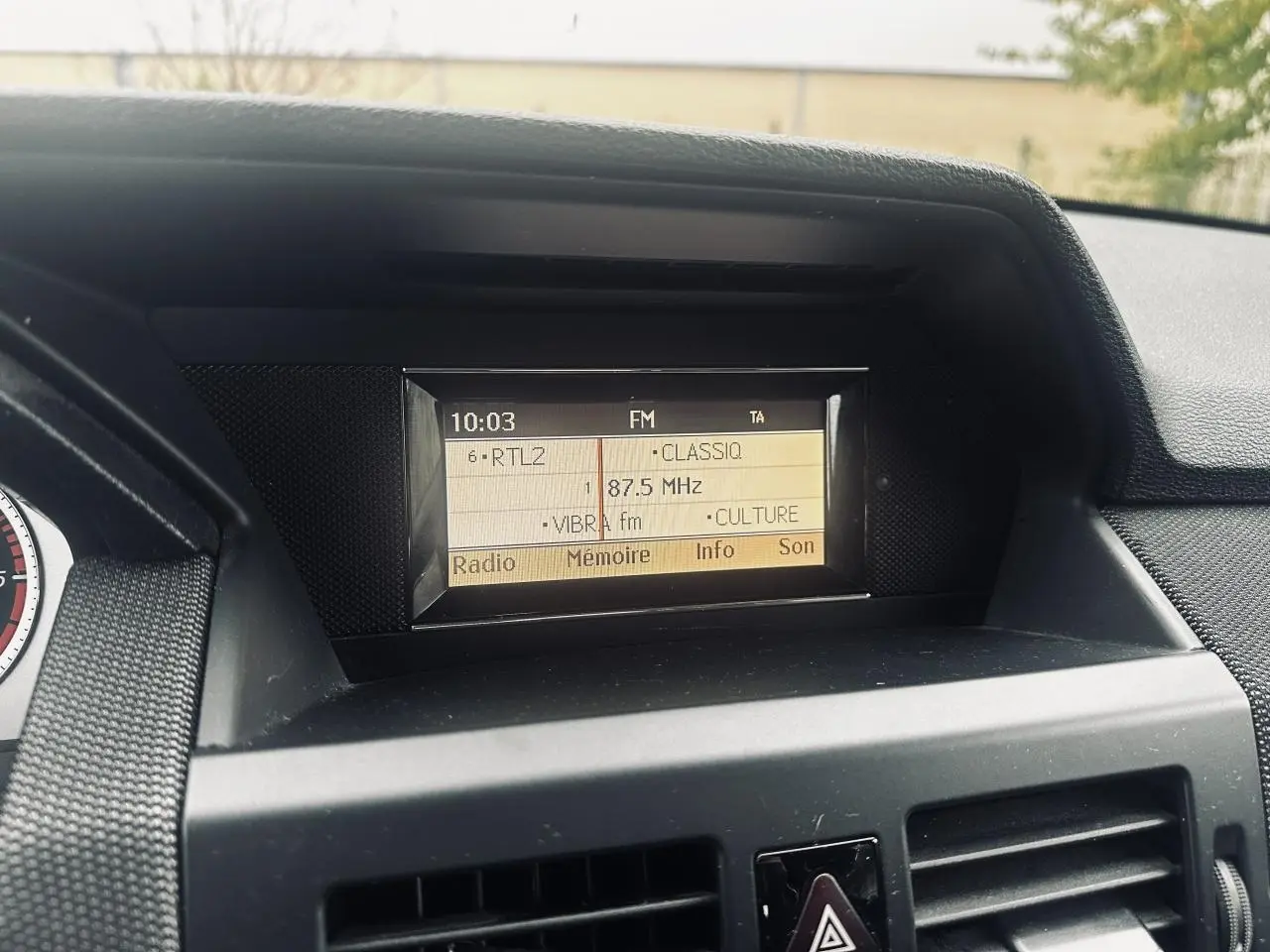 Écran central de l'autoradio Audio 20 du Mercedes GLK 220 CDI noir, affichant fréquence FM 87,5 MHz.
