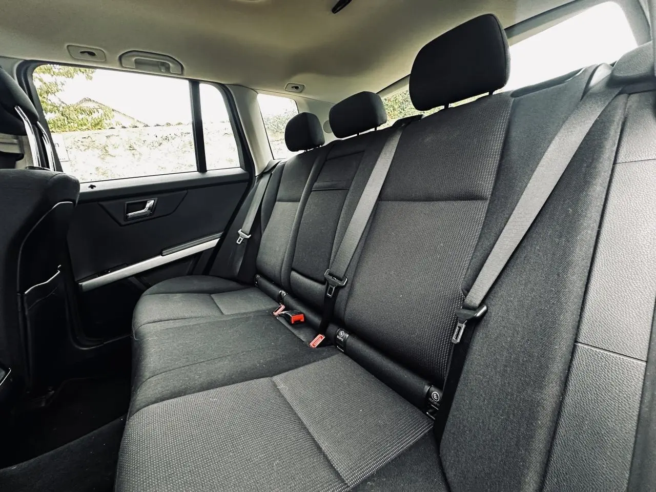 Vue latérale gauche de la banquette arrière noire du Mercedes GLK 220 CDI avec ceintures trois points et appuie-têtes.