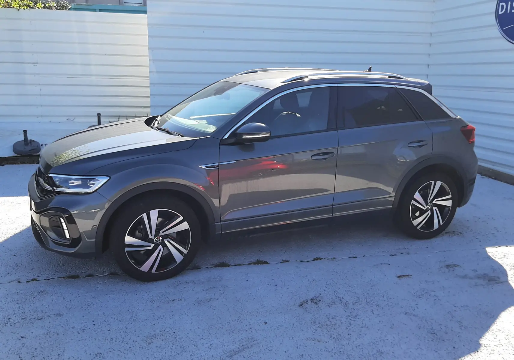 Volkswagen T-Roc 2.0 TDI R-Line gris Indium vu de profil côté gauche, avec jantes alliage bicolores et toit noir.