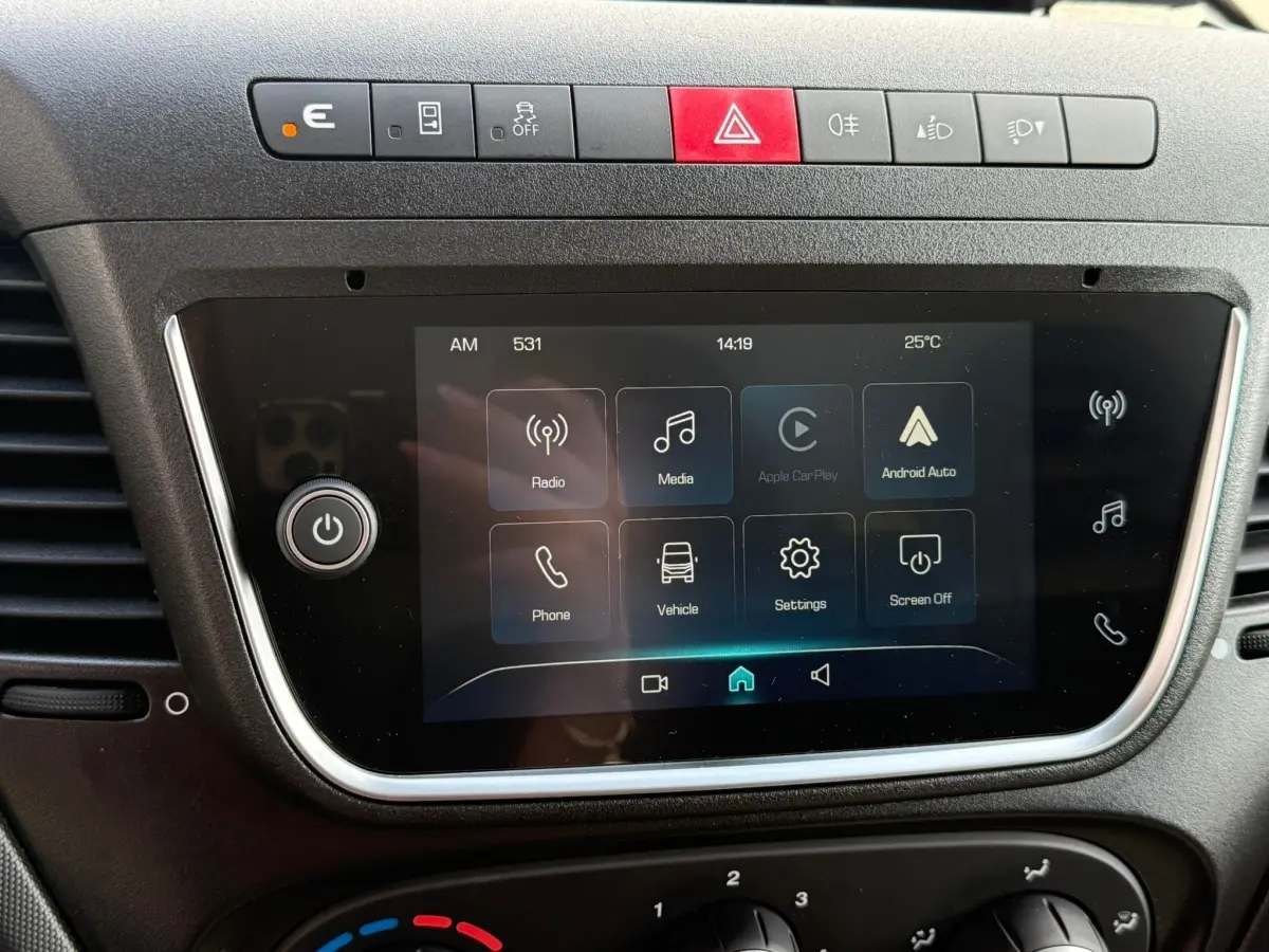 Écran tactile central avec commandes multimédia et boutons de sécurité sur le tableau de bord du Iveco Daily blanc 2026.