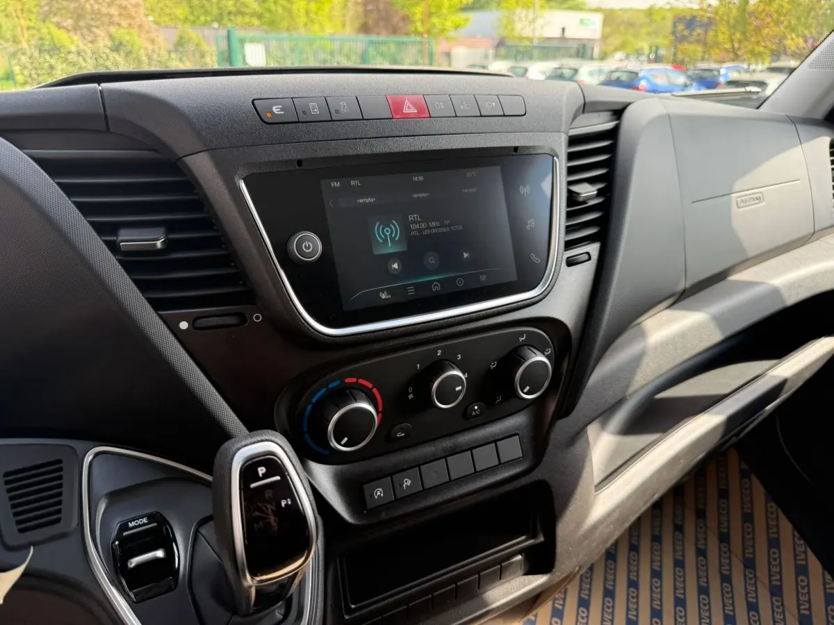 Vue rapprochée de la console centrale et levier de vitesse automatique du tableau de bord noir du Iveco Daily blanc 2026.