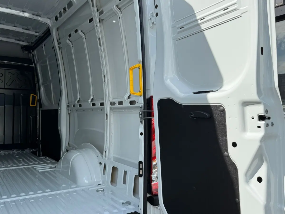 Vue intérieure arrière droite du fourgon Iveco Daily blanc 2026, montrant la zone de chargement vide avec poignée jaune.