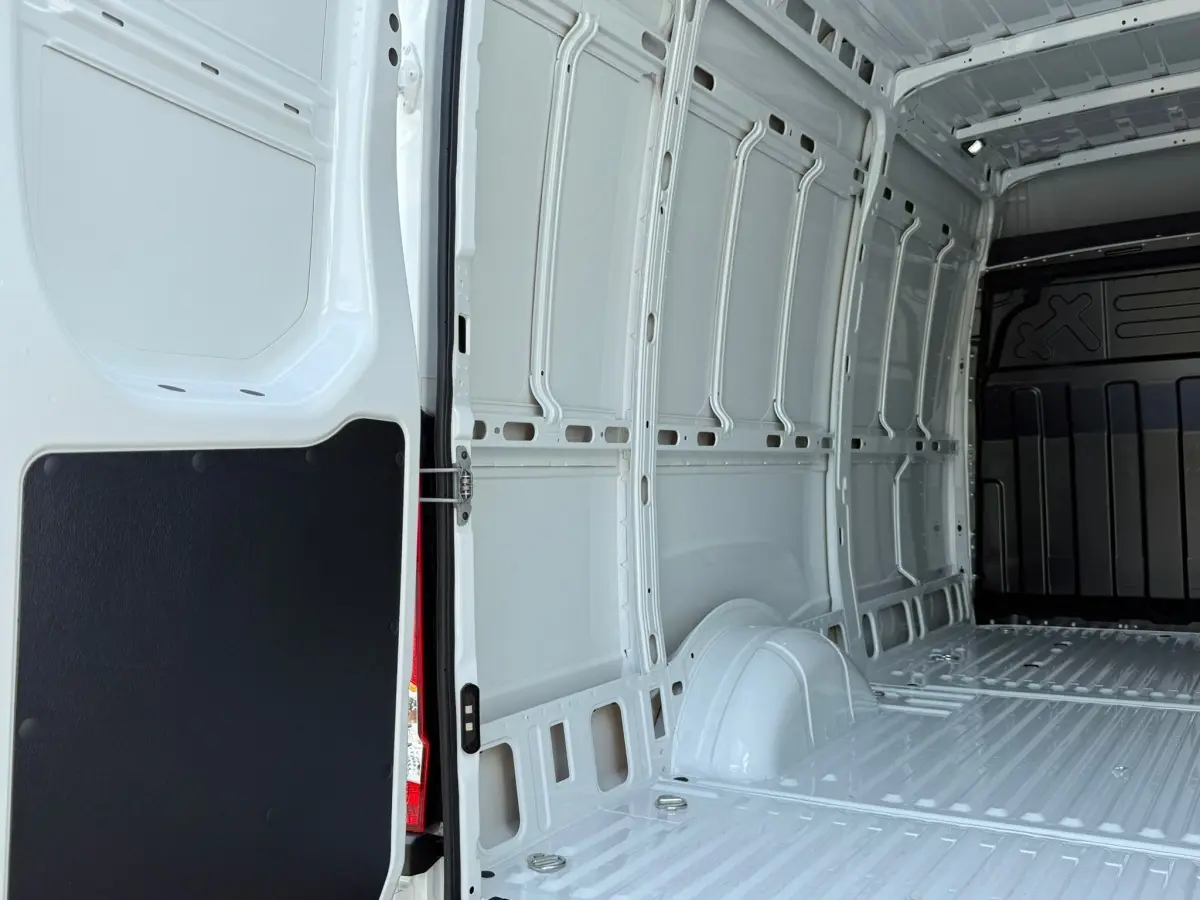 Vue intérieure arrière du fourgon Iveco Daily blanc 2026, montrant l’espace de chargement vide et les parois métalliques.