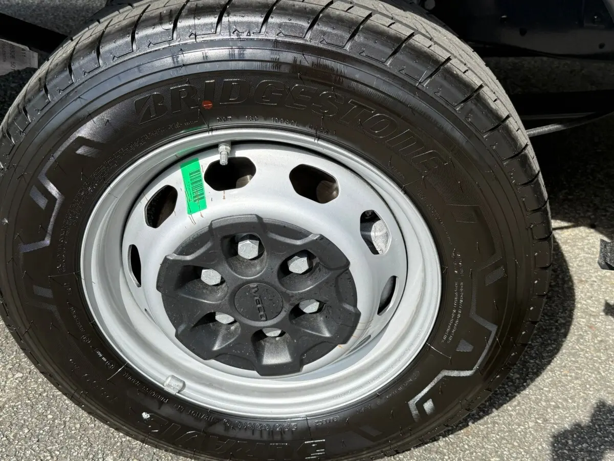 Gros plan sur la roue avant droite de l'IVECO Daily blanc, mettant en valeur la jante acier et le pneu Bridgestone.