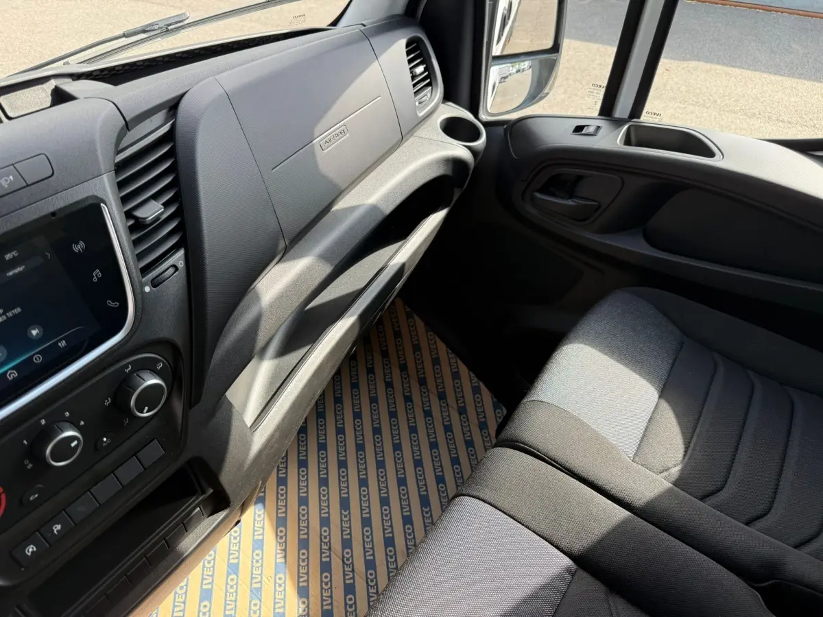 Intérieur côté passager de l’Iveco Daily 2026, tableau de bord noir et siège tissu gris en lumière naturelle.