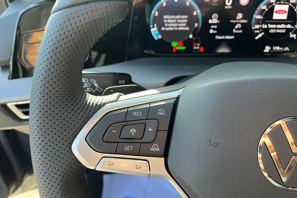 Gros plan sur le volant cuir multifonctions côté gauche de la Volkswagen Golf gris dauphin avec tableau de bord numérique.
