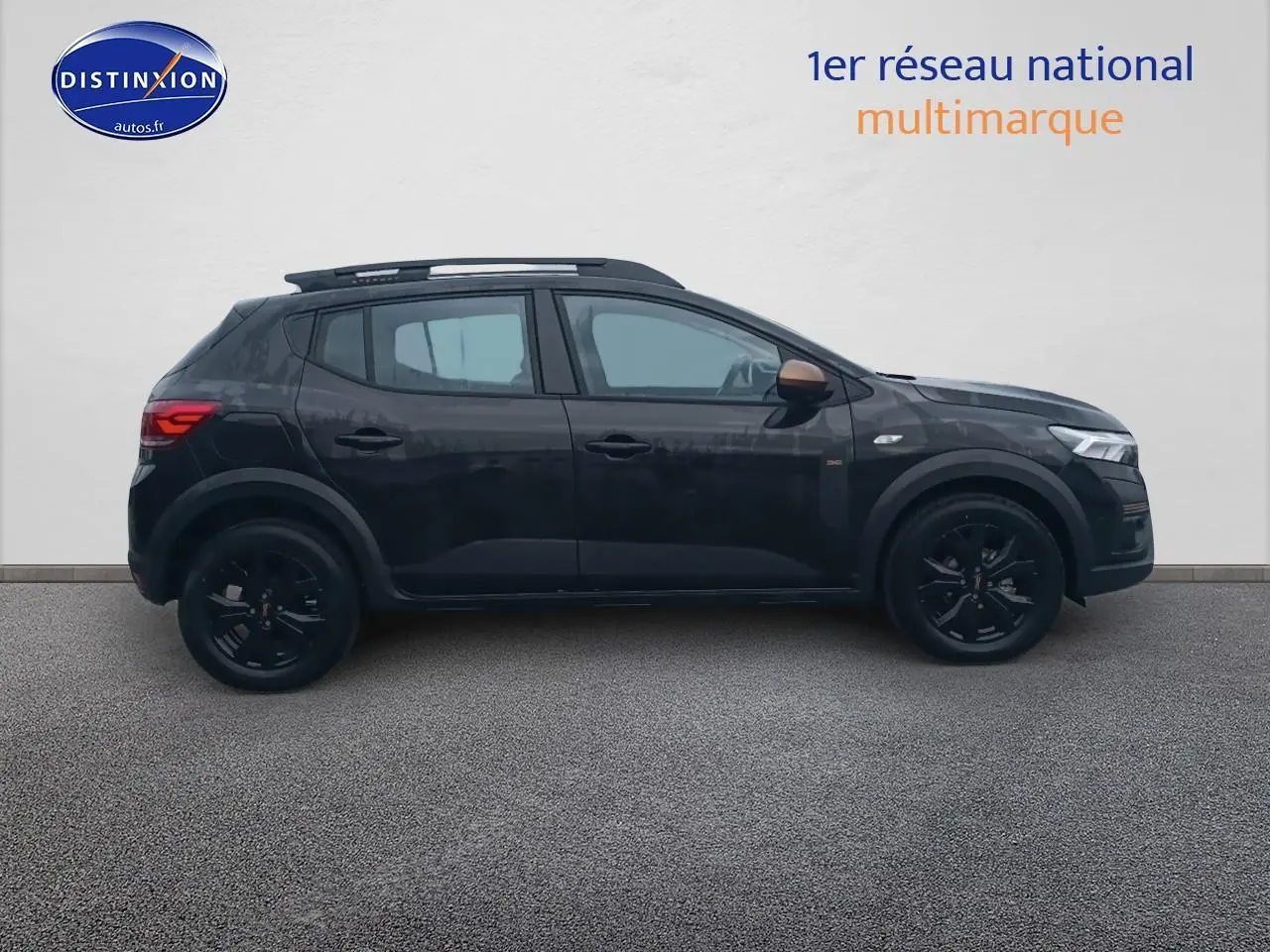 Profil côté gauche d'une Dacia Sandero Stepway noire 2025 avec jantes noires et barres de toit visibles.
