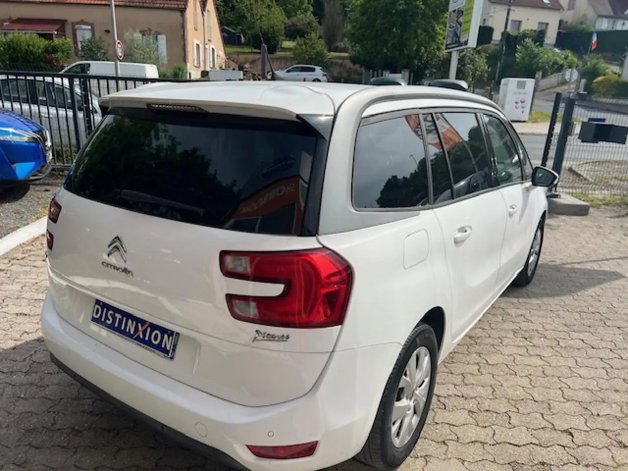 Vue 3/4 arrière droite d'un Citroën Grand C4 Picasso blanc avec vitres surteintées et jantes alliage 16 pouces.