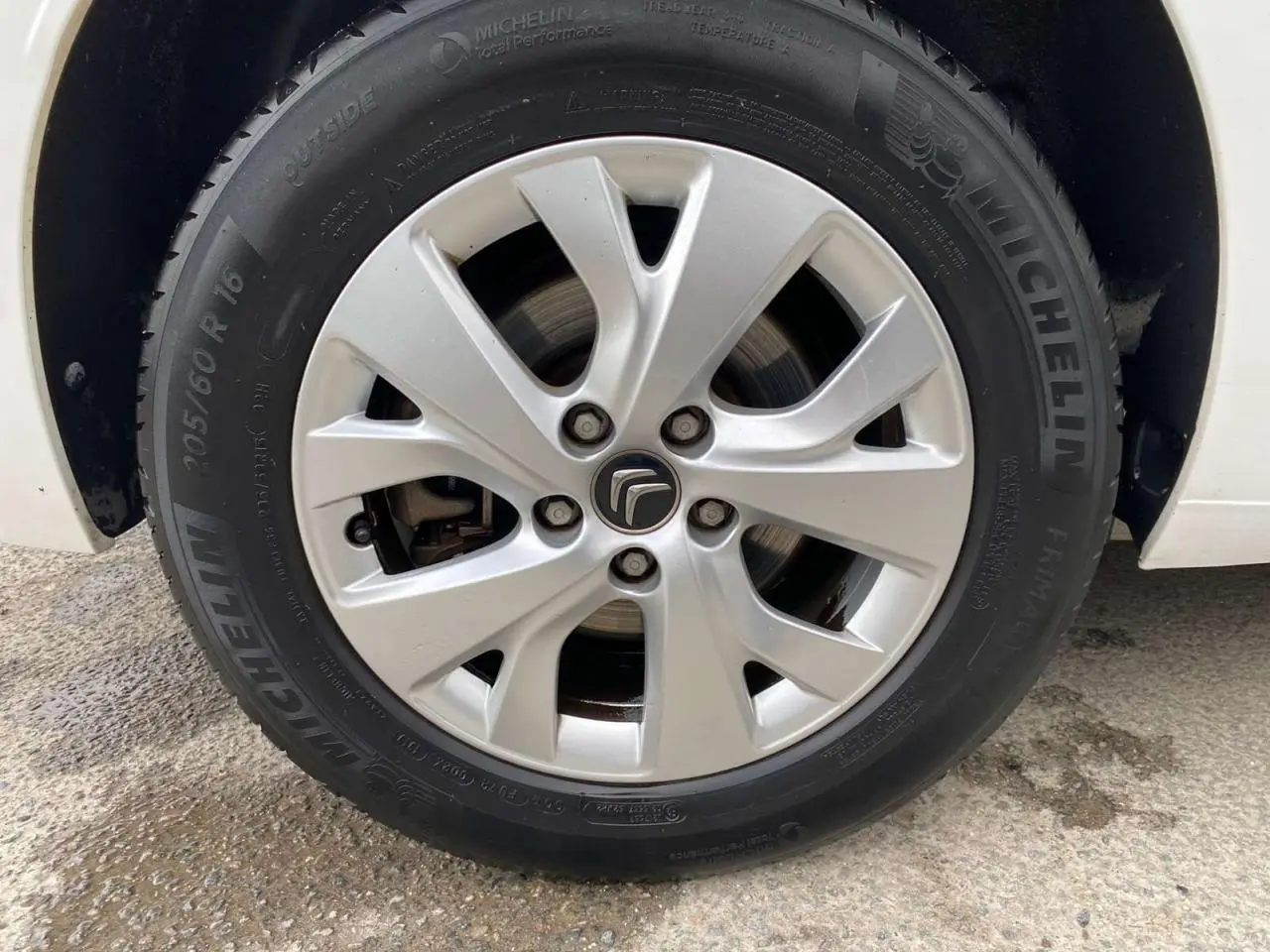 Gros plan sur la jante alliage 16 pouces Notos argentée du côté gauche d'un Citroën Grand C4 Picasso blanc.