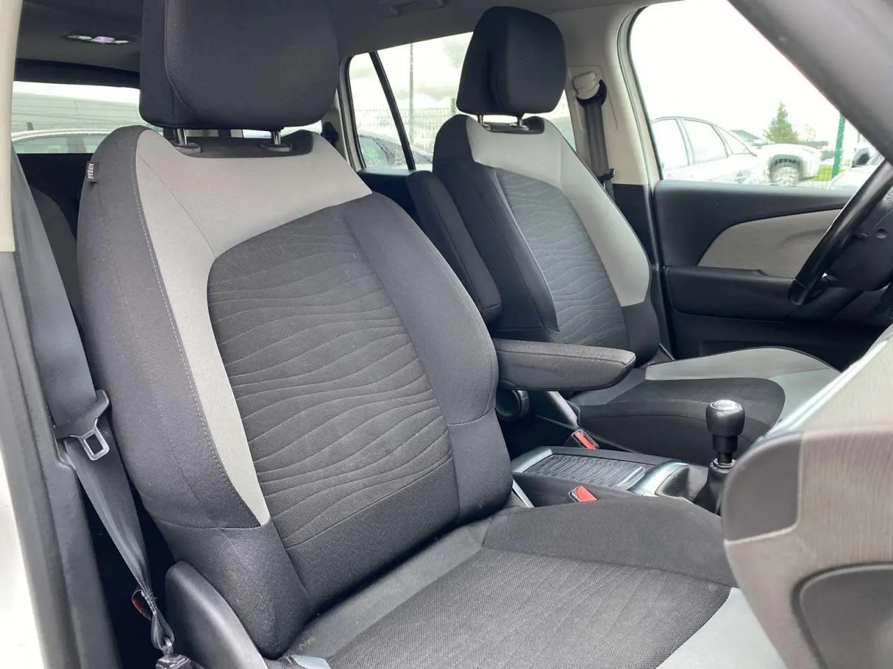 Vue intérieure rapprochée des sièges avant gris et noir du Citroën Grand C4 Picasso 2015, version Intensive.