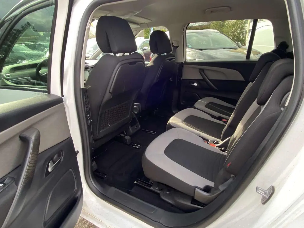 Vue intérieure côté droit du Citroën Grand C4 Picasso blanc, montrant les sièges de la deuxième rangée en tissu bicolore.