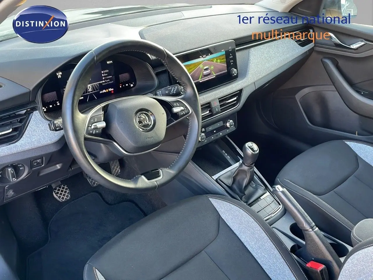 Intérieur avant droit du Skoda Kamiq 2024 gris graphite, volant multifonction, écran tactile et boîte manuelle visible.