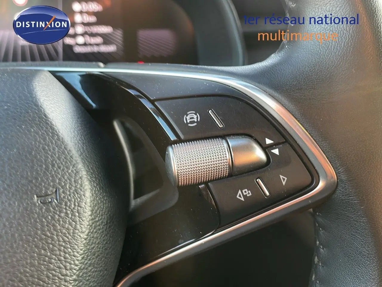 Gros plan sur les commandes du volant noir du Skoda Kamiq 2024, avec molette métallique et boutons multifonctions.