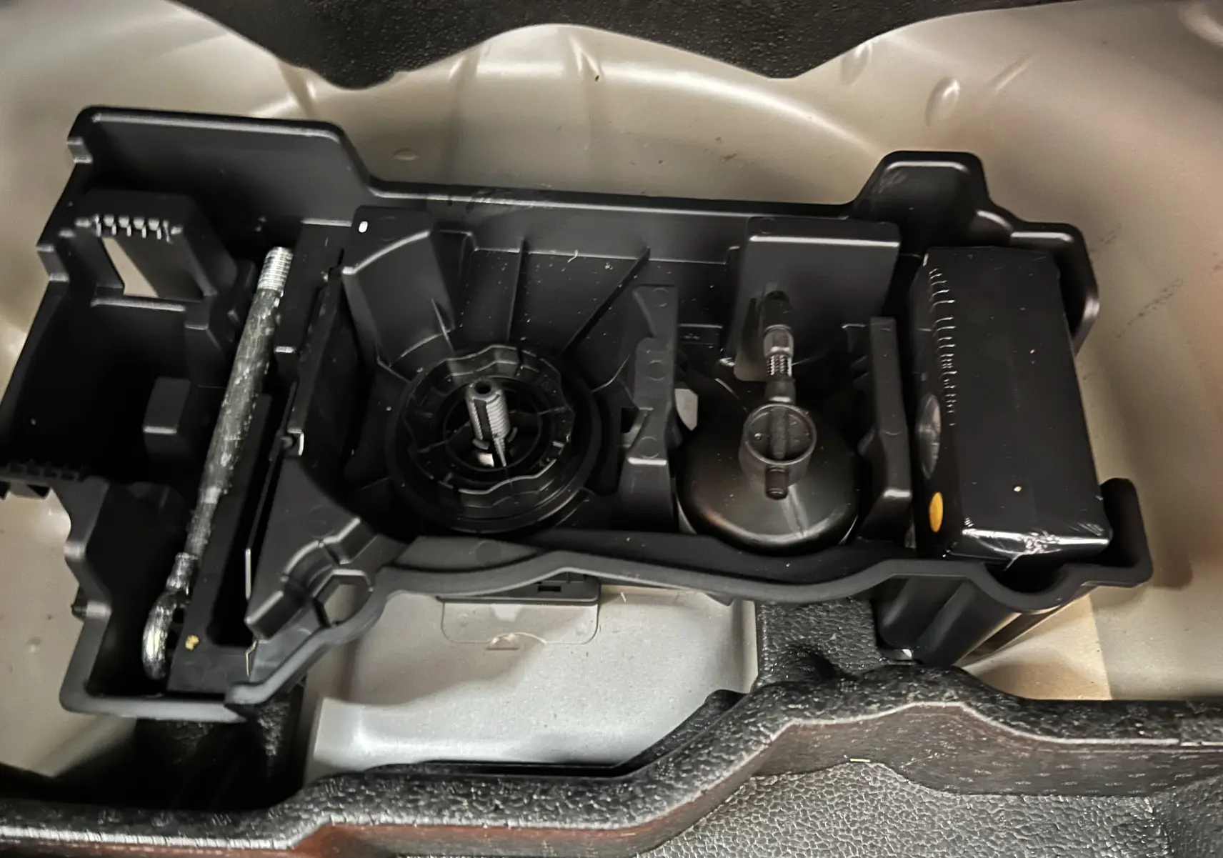 Rangement d’outils en plastique noir dans le coffre d’un Peugeot 2008 gris Artense, vue de dessus rapprochée.