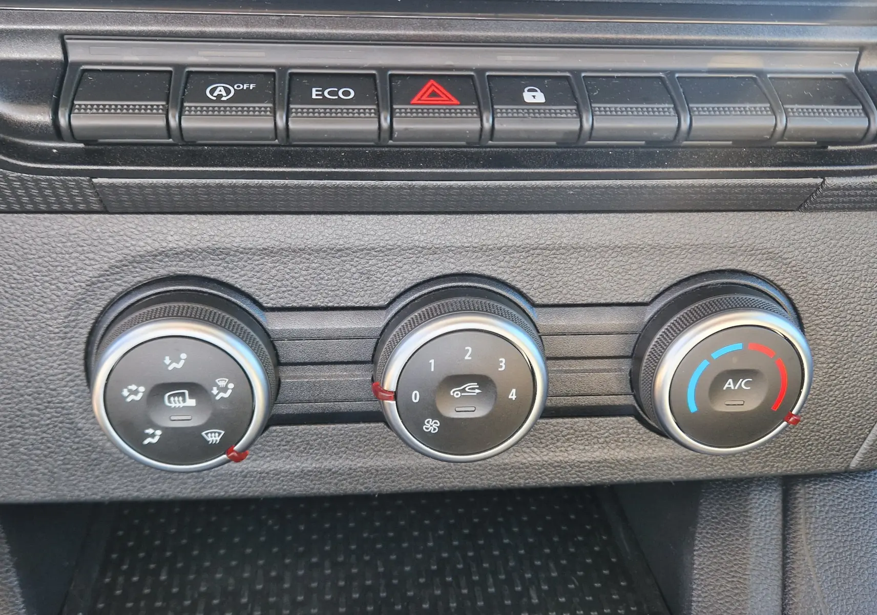 Gros plan sur les commandes de climatisation manuelles du Renault Kangoo 2024, avec boutons rotatifs et touches fonctionnelles.