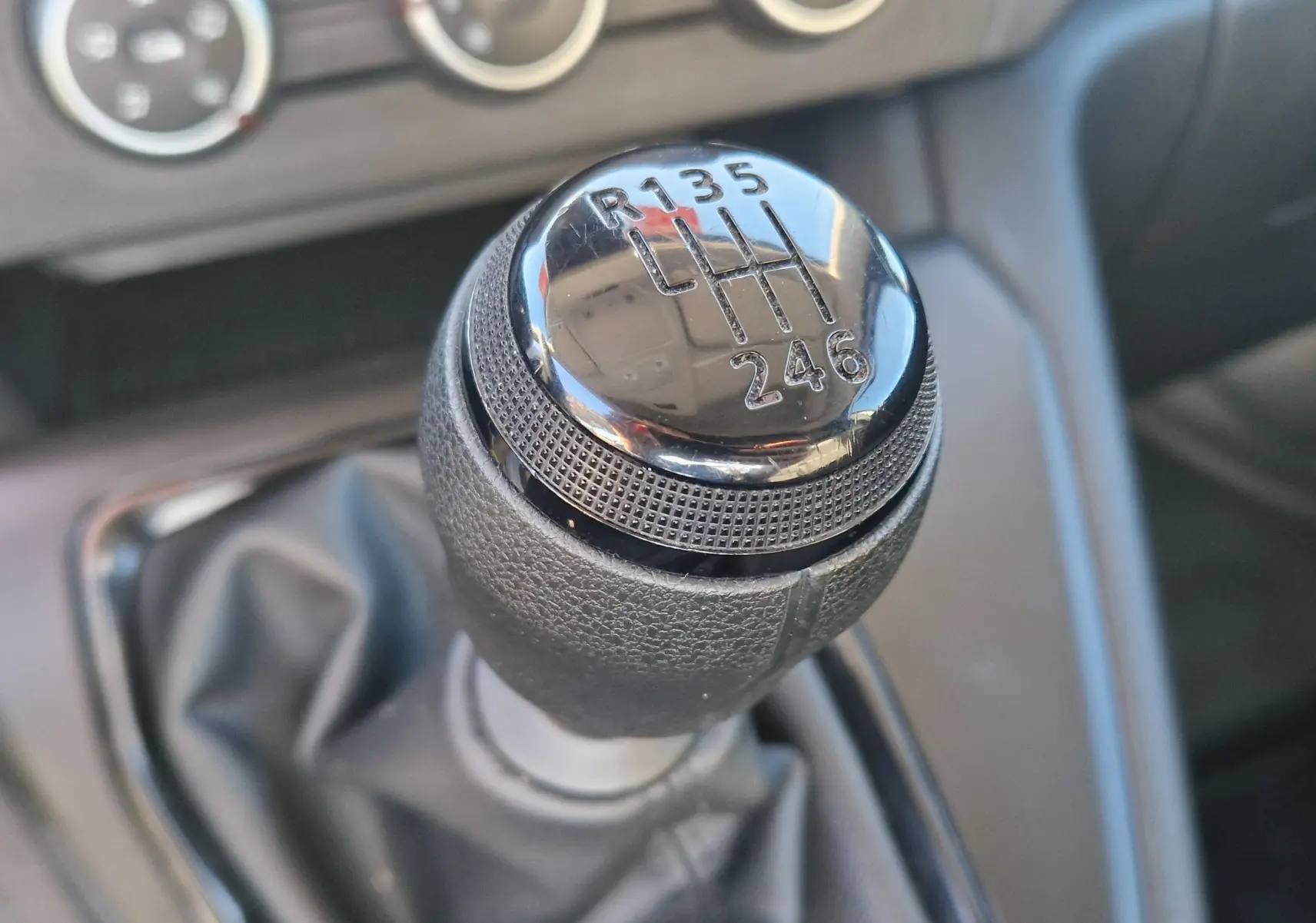 Gros plan sur le levier de vitesses manuel noir du Renault Kangoo 2024, montrant les six rapports et la marche arrière.