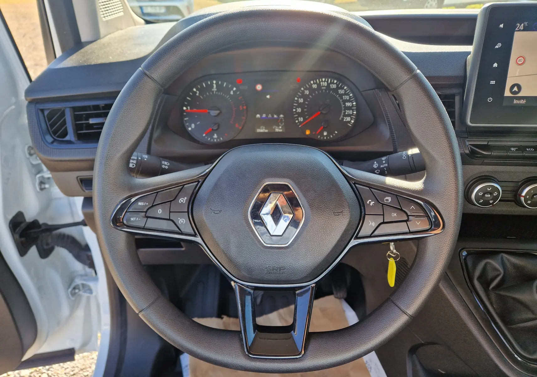 Vue intérieure centrée sur le volant noir du Renault Kangoo blanc 2024, avec tableau de bord et écran tactile visibles.