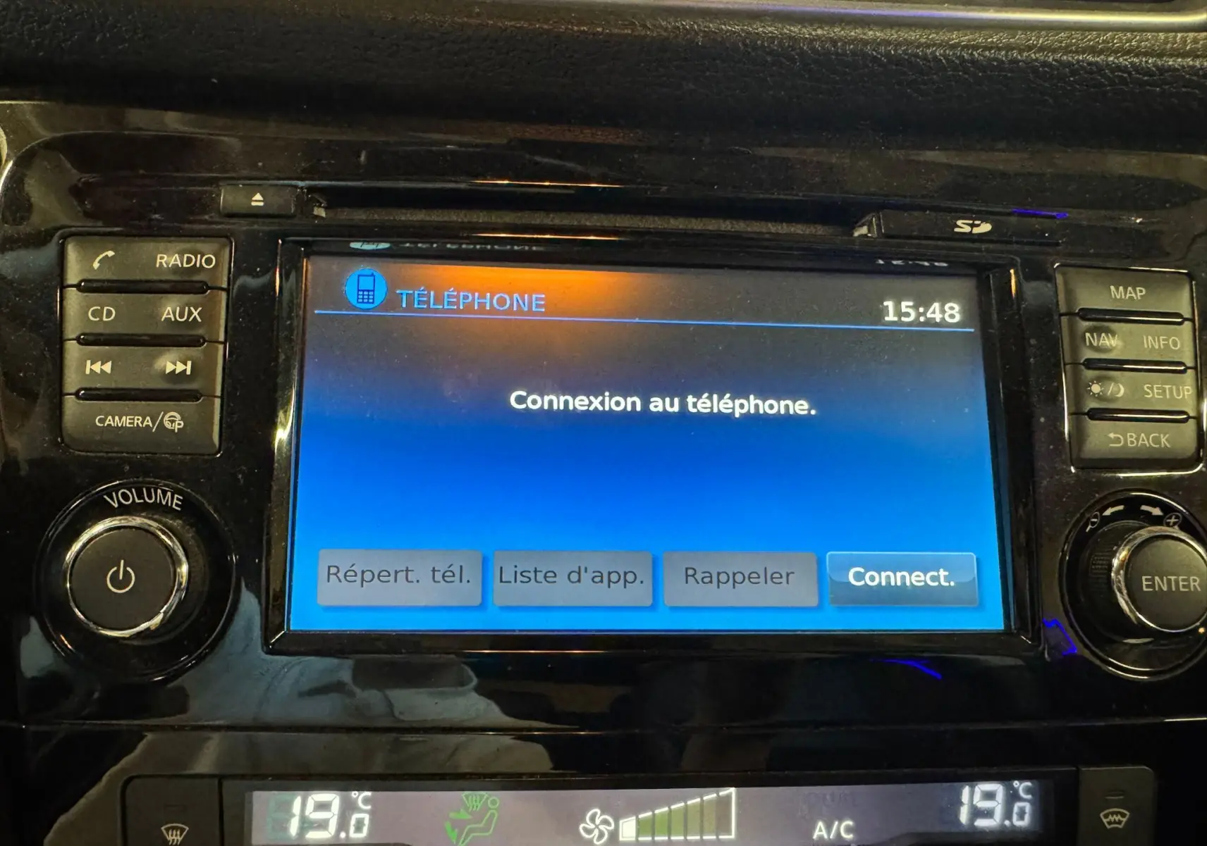 Écran tactile central du Nissan Qashqai noir, affichant la connexion au téléphone, avec commandes audio et climatisation visibles.