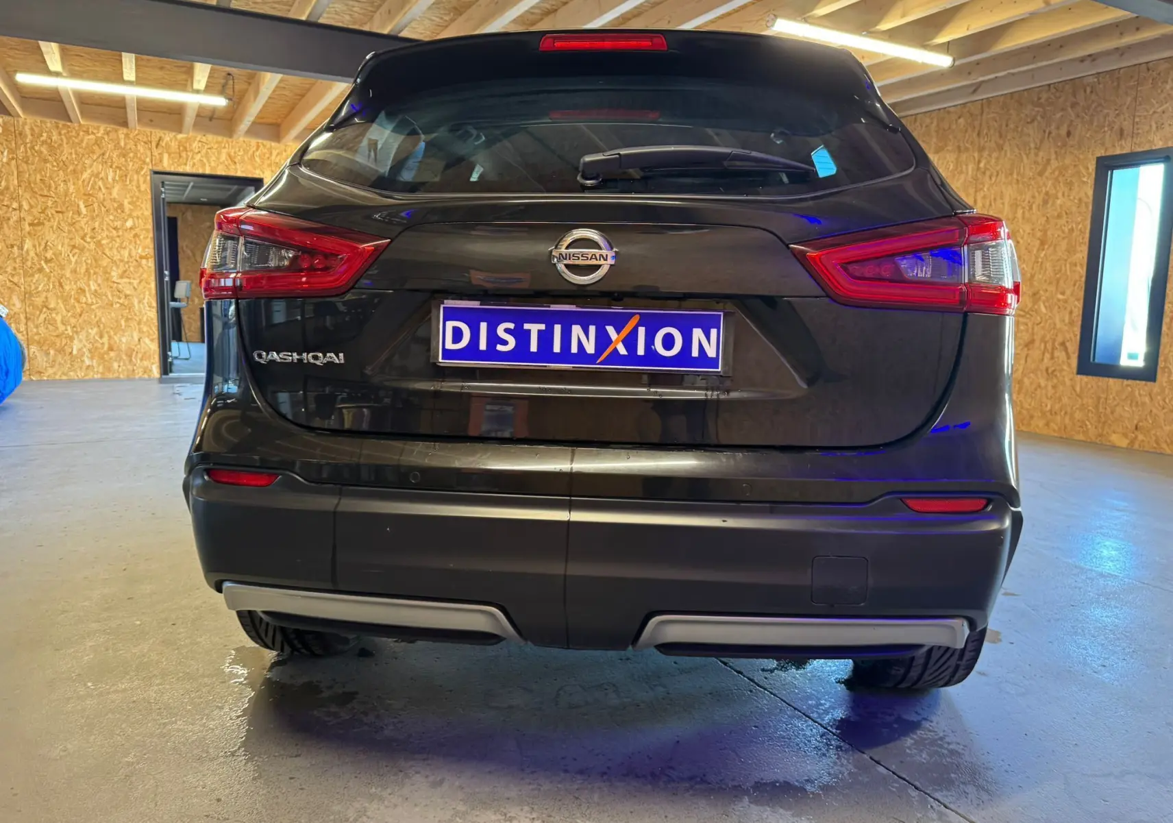 Vue arrière d'un Nissan Qashqai noir 2017 dans un garage avec feux arrière et logo visibles.