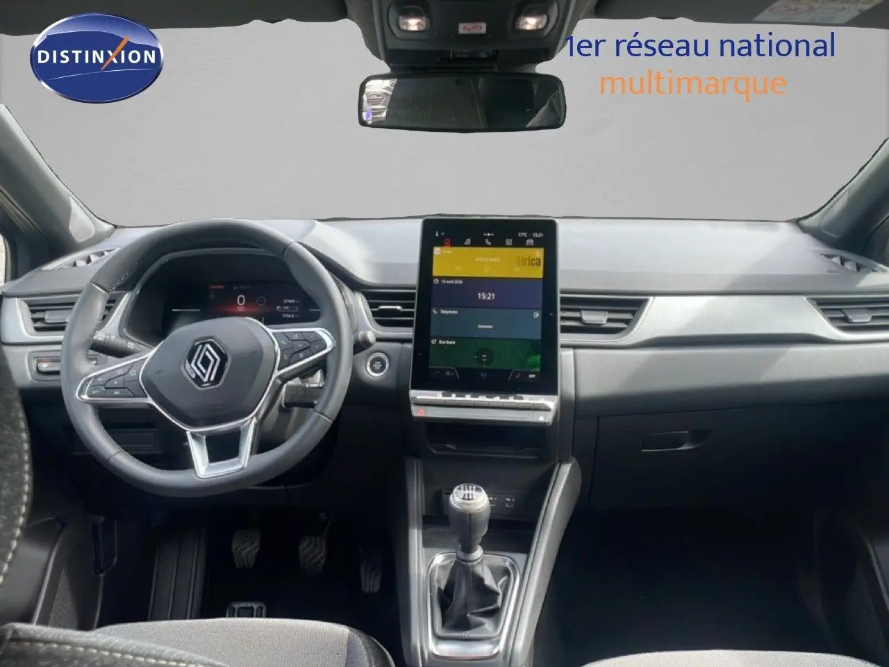 Vue intérieure frontale du Renault Captur 2025, tableau de bord noir avec écran tactile vertical et levier de vitesses manuel.