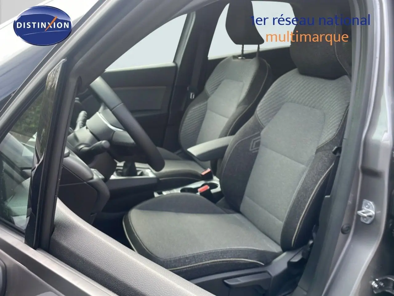 Vue intérieure côté conducteur du Renault Captur 2025 gris Cassiopée avec sièges tissu gris et volant multifonction.