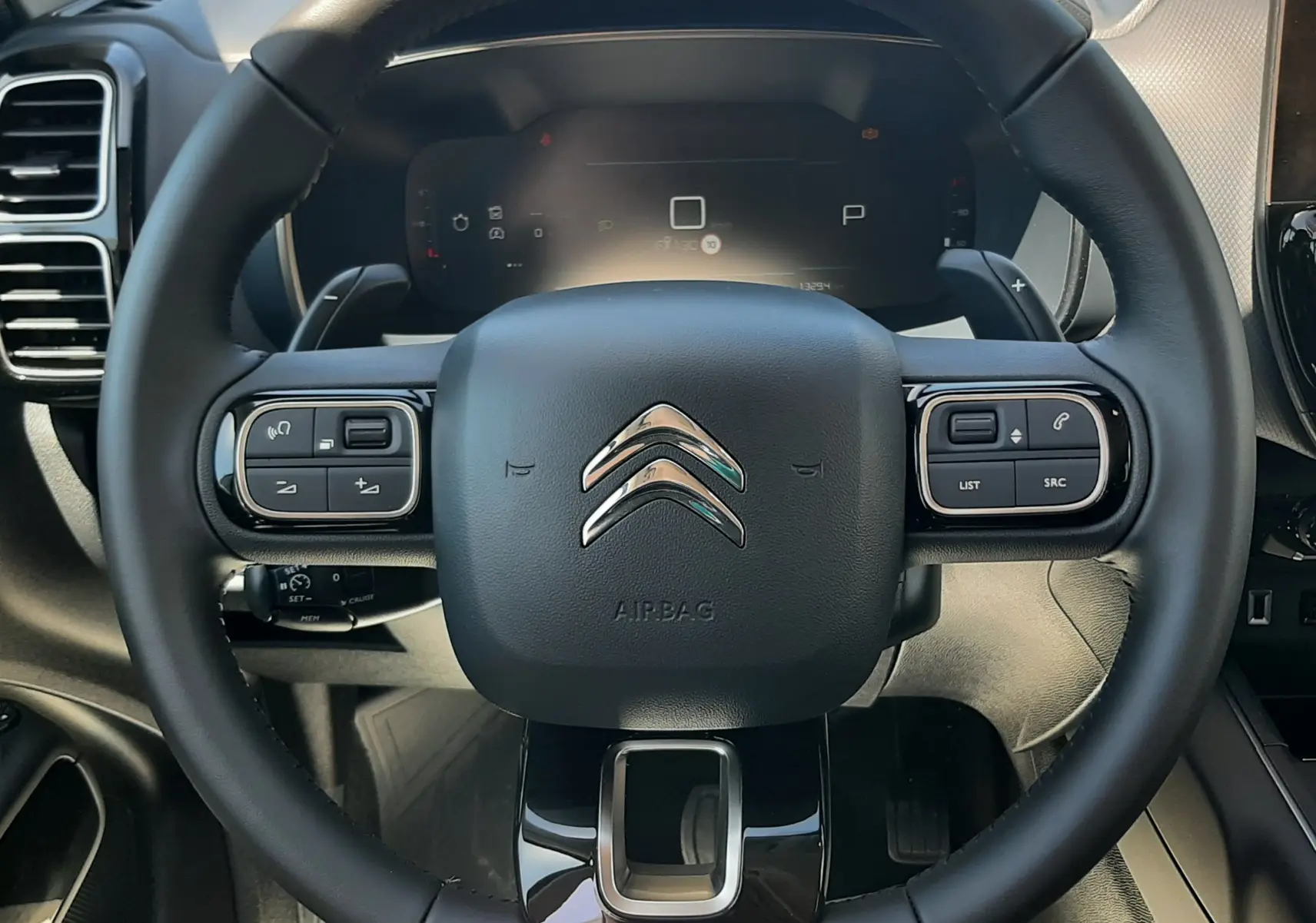Vue rapprochée du volant noir du Citroën C5 Aircross Ph.2 Hybrid 145ch, avec commandes intégrées et tableau de bord numérique.