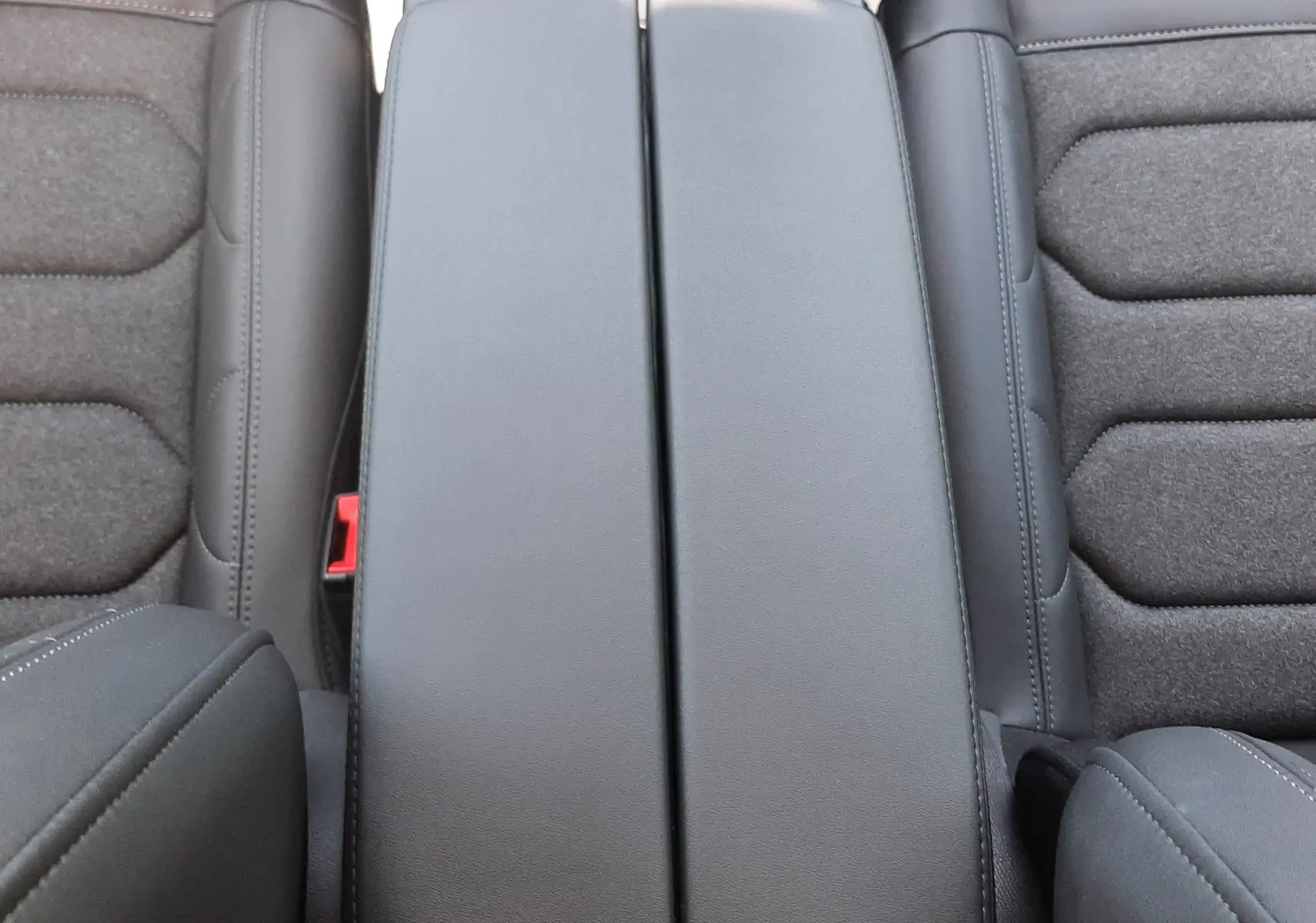 Vue plongeante sur l'accoudoir central noir et les sièges gris foncé du Citroën C5 Aircross Ph.2 Hybrid 2025.
