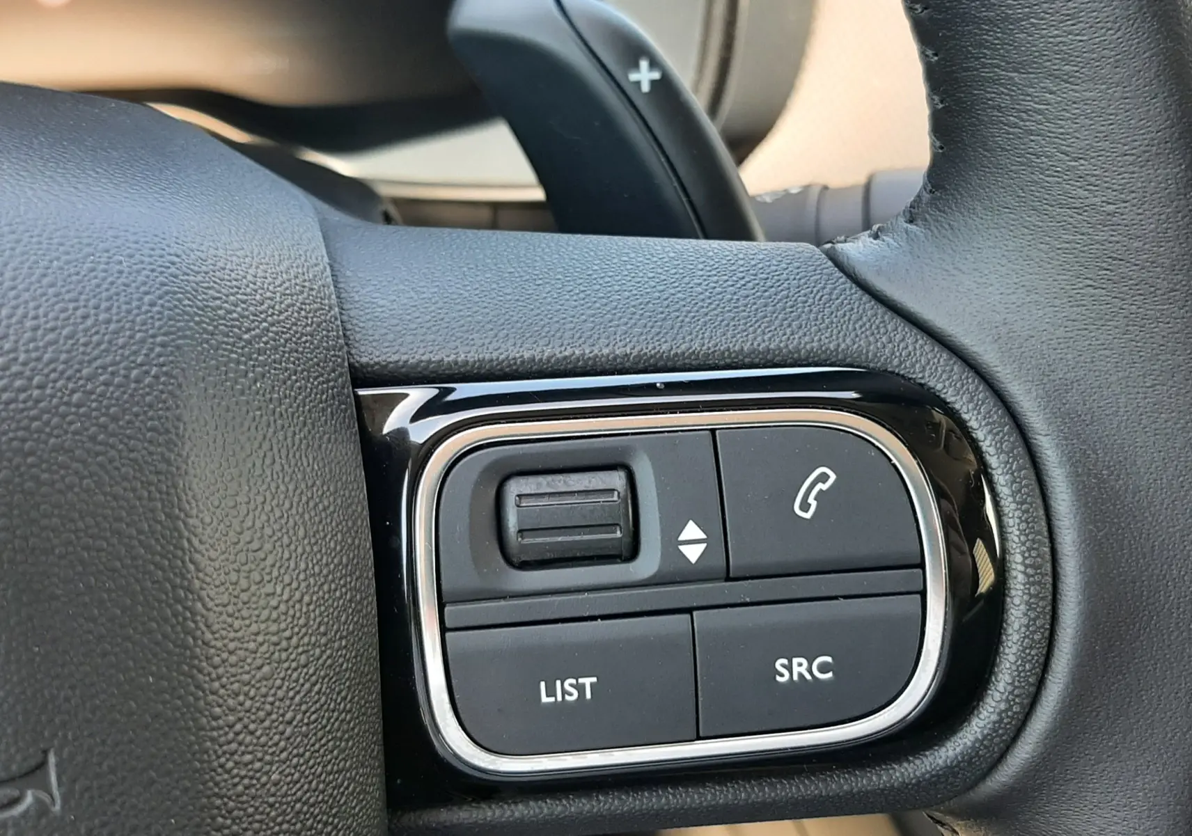 Gros plan sur les commandes multifonctions noires du volant cuir du Citroën C5 Aircross Ph.2 Hybrid 2025.