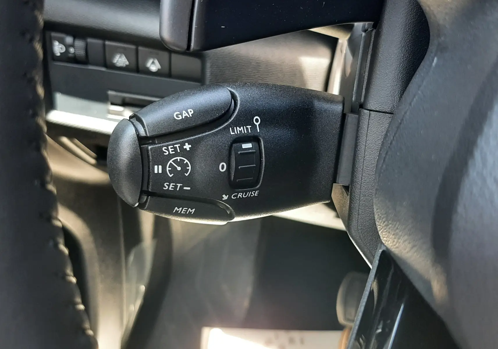 Gros plan sur la commande de régulateur de vitesse à gauche du volant dans le Citroën C5 Aircross noir Perla Nera 2025.