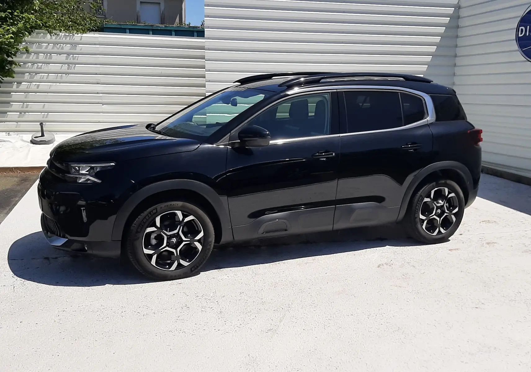 Vue de profil côté gauche d'un Citroën C5 Aircross noir Perla Nera avec jantes bicolores et toit ouvrant panoramique.