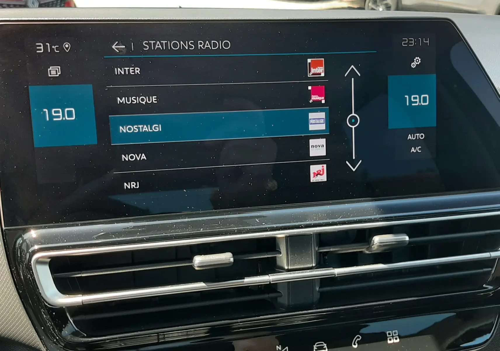 Écran central tactile du Citroën C5 Aircross noir, affichant les stations radio avec commandes climatisation visibles.