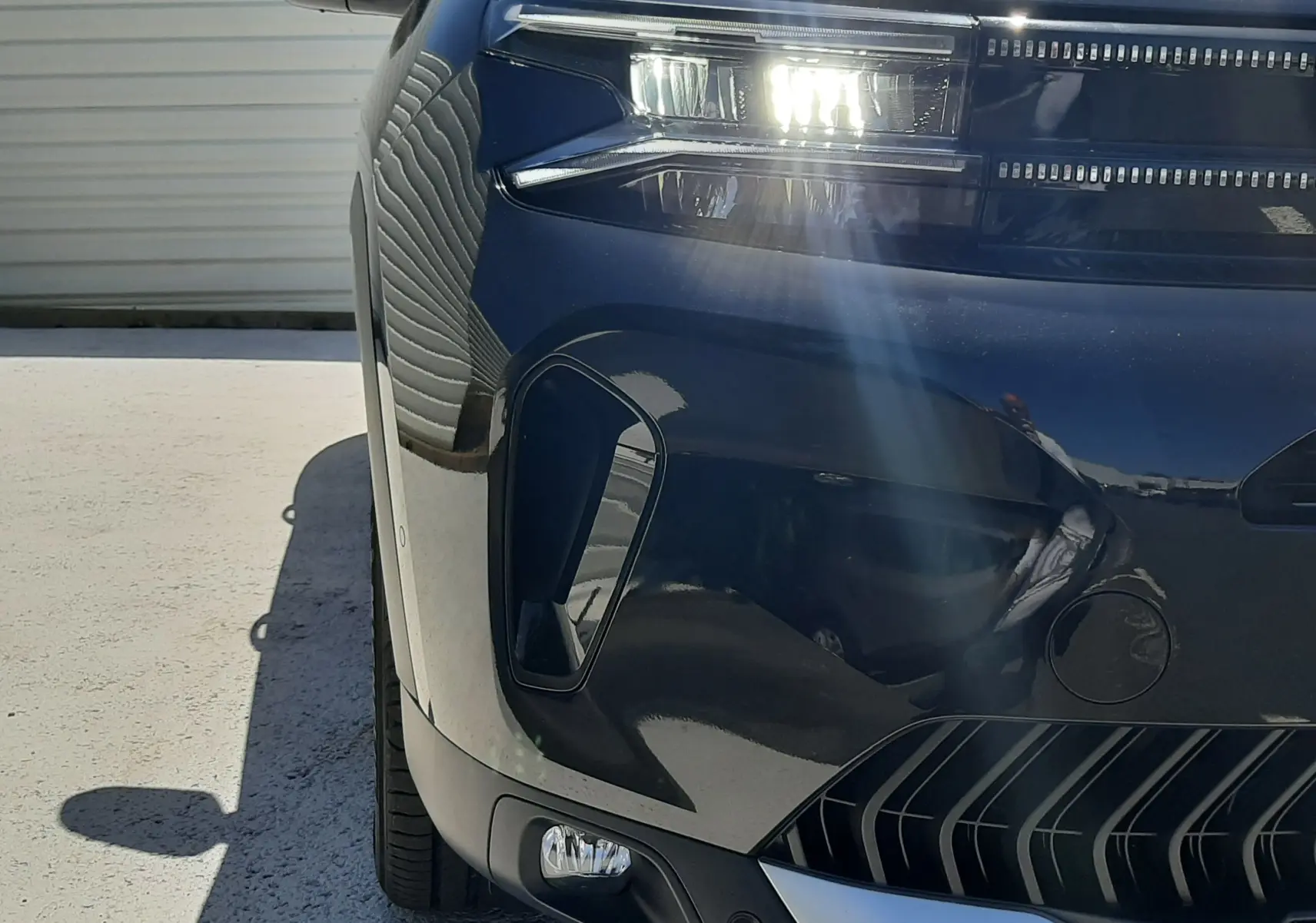 Gros plan sur l’avant droit noir perla nera du Citroën C5 Aircross 2025 avec phares LED allumés et calandre distinctive.