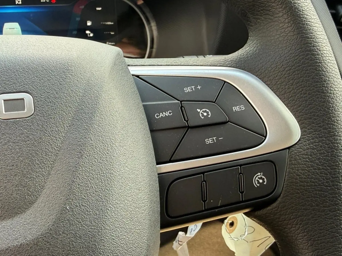 Gros plan sur le côté droit du volant noir de l'Iveco Daily 2.3 35S16 V12, avec commandes de régulateur de vitesse.