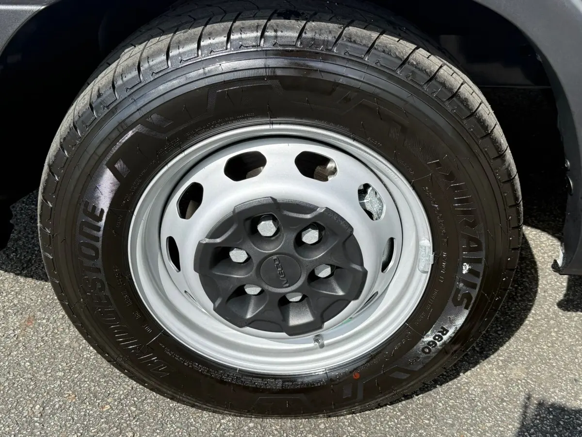 Gros plan sur la roue avant droite du fourgon Iveco Daily blanc 2026, pneu Bridgestone et jante acier grise.