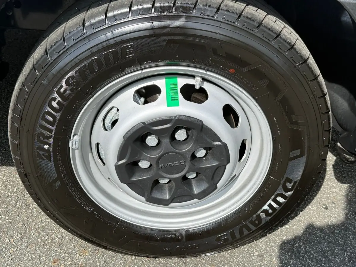 Gros plan sur la roue avant droite du Iveco Daily blanc 2026, pneu Bridgestone et jante acier grise avec cache central noir.