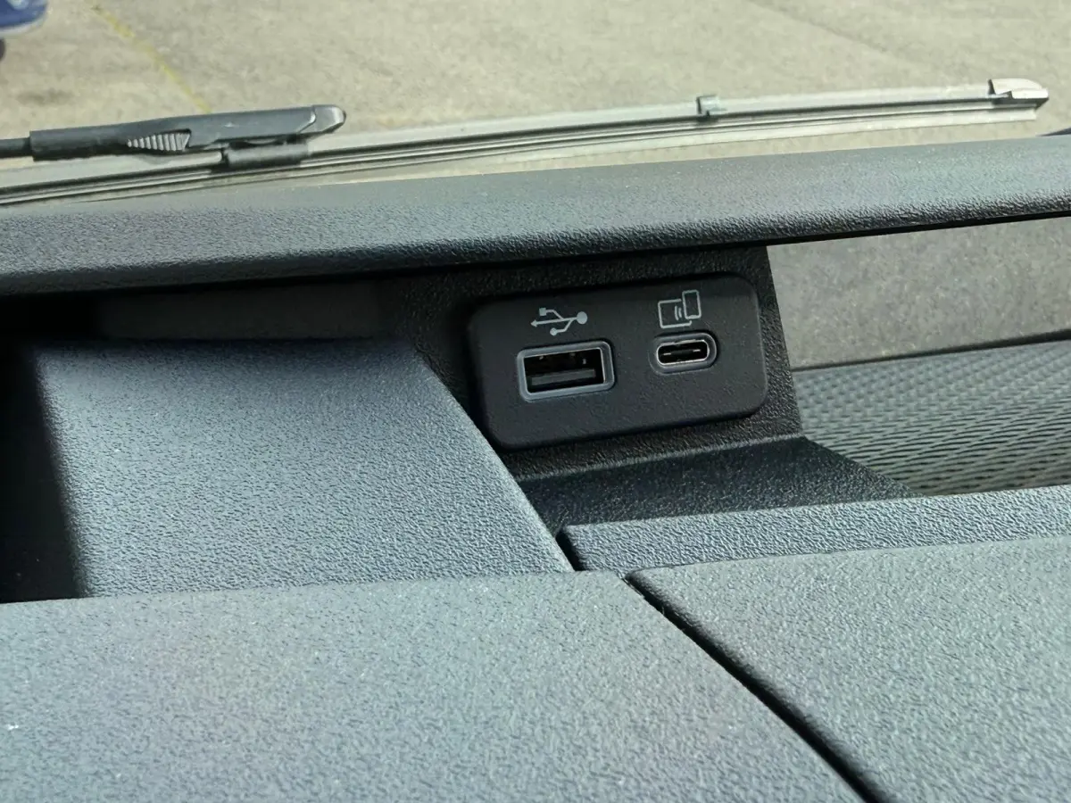 Gros plan sur les ports USB et USB-C du tableau de bord noir du Iveco Daily blanc 2026, vue intérieure frontale.