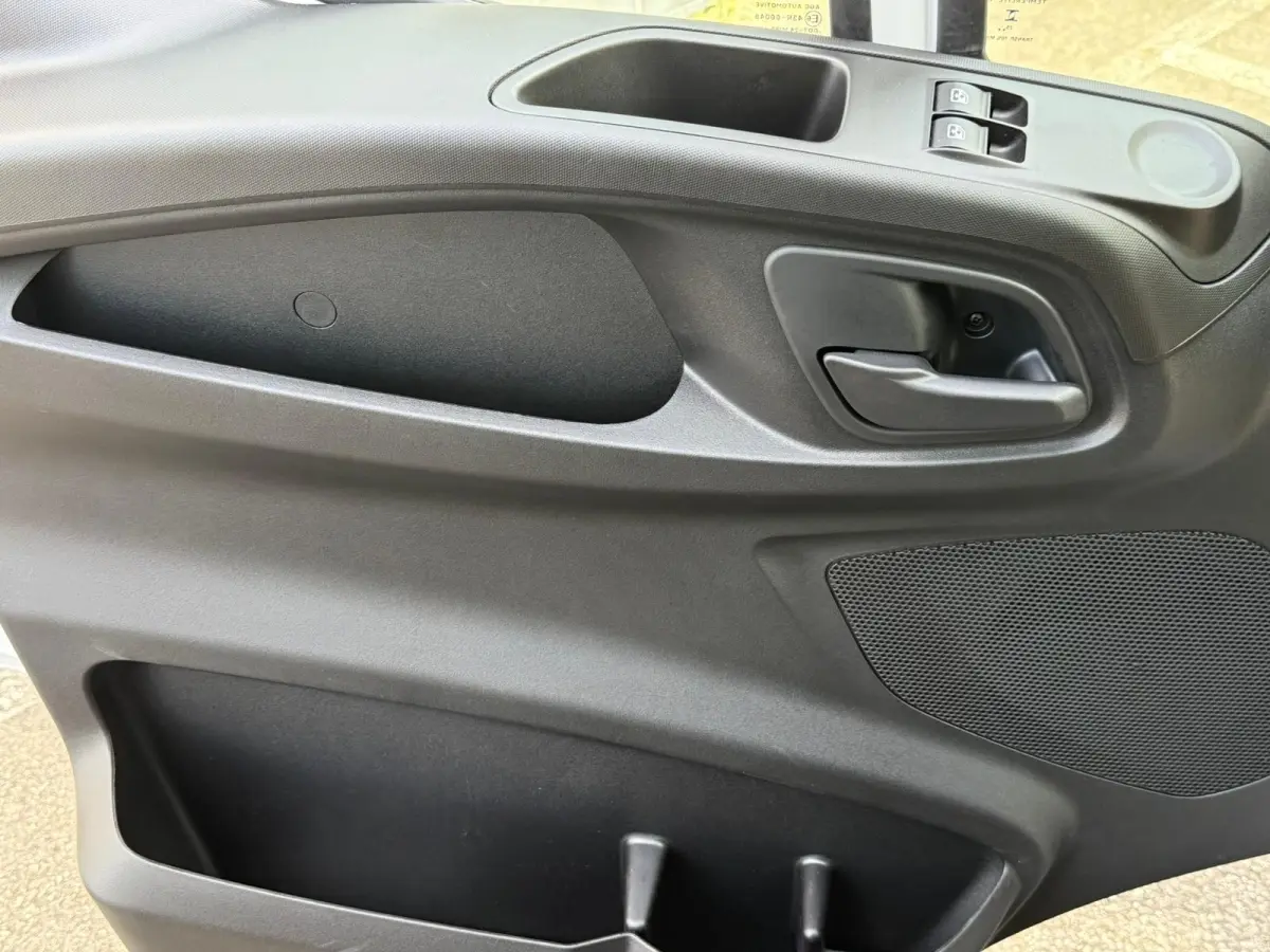 Vue rapprochée de la porte intérieure côté conducteur de l'Iveco Daily 2026, avec poignée, commandes de vitres et rangement noir.