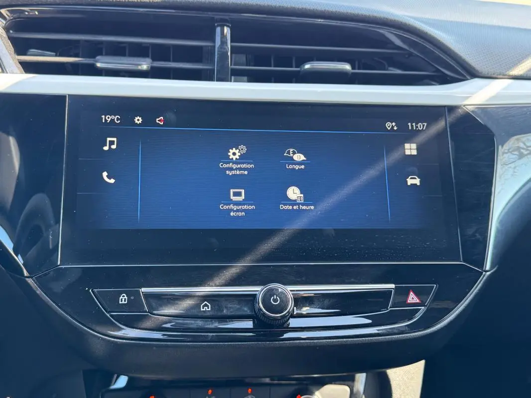 Écran tactile central de l’Opel Corsa 2025 affichant les réglages système, avec boutons de commande en dessous.