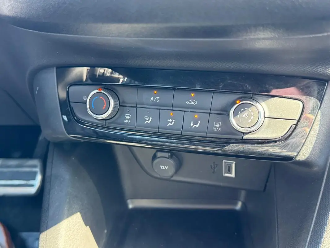 Gros plan sur la console centrale de l’Opel Corsa 2025, montrant les commandes de climatisation et les ports USB et 12V.