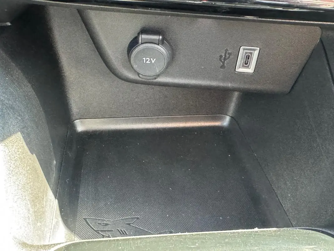 Gros plan sur la prise 12V et port USB-C dans le compartiment de rangement intérieur de l’Opel Corsa rouge 2025.