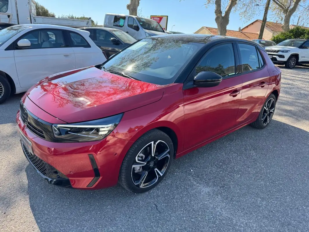 Opel Corsa rouge 2025 vue 3/4 avant droit, avec jantes noires et toit noir contrasté.