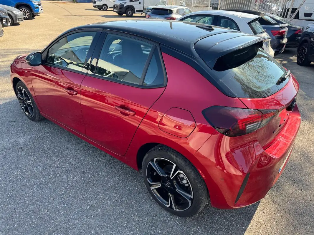 Opel Corsa 2025 rouge vue 3/4 arrière droit, toit noir contrasté et jantes alliage noires distinctives.