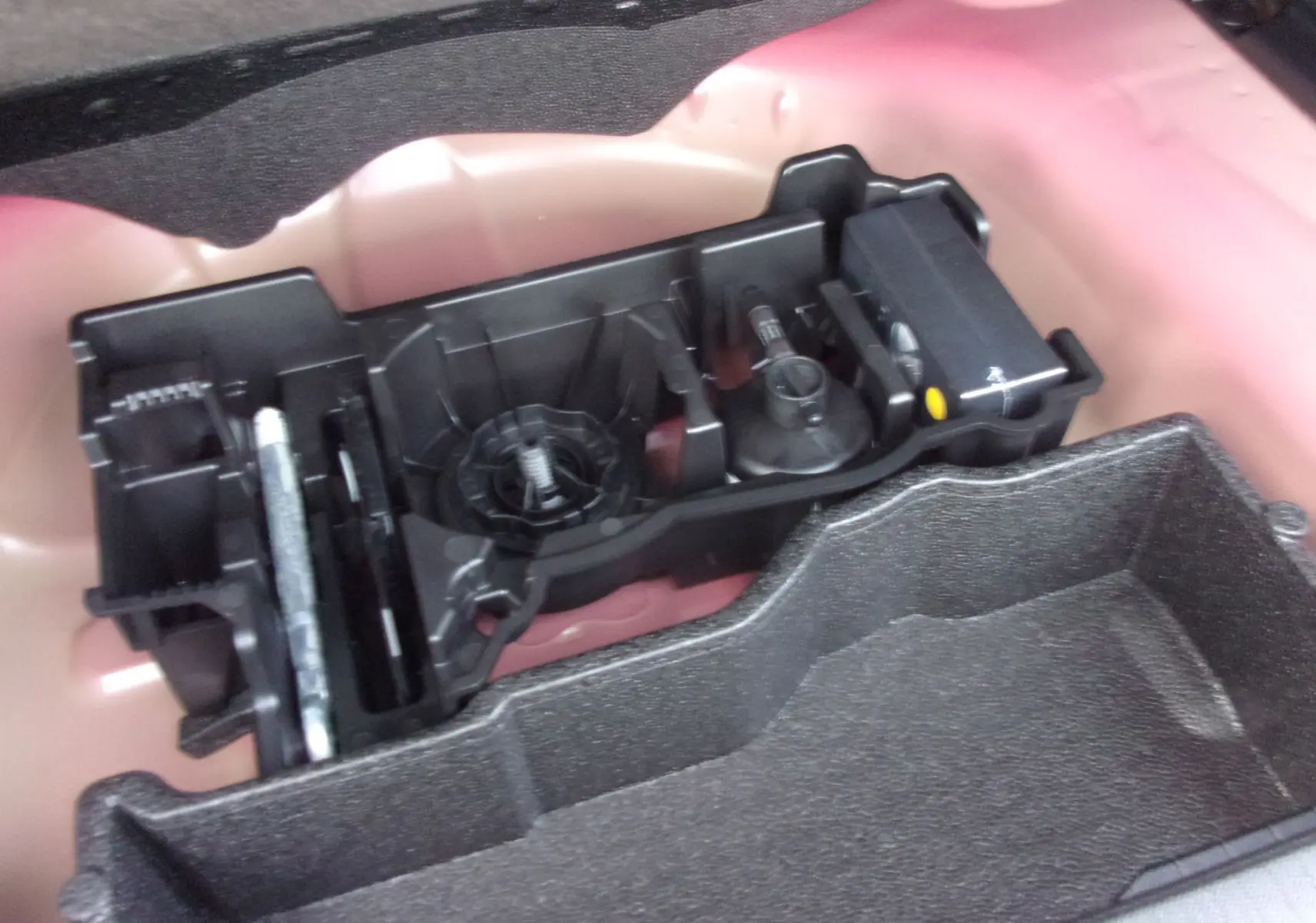 Gros plan sur le rangement à outils dans le coffre du Peugeot 2008 Rouge Elixir, version diesel 2024.