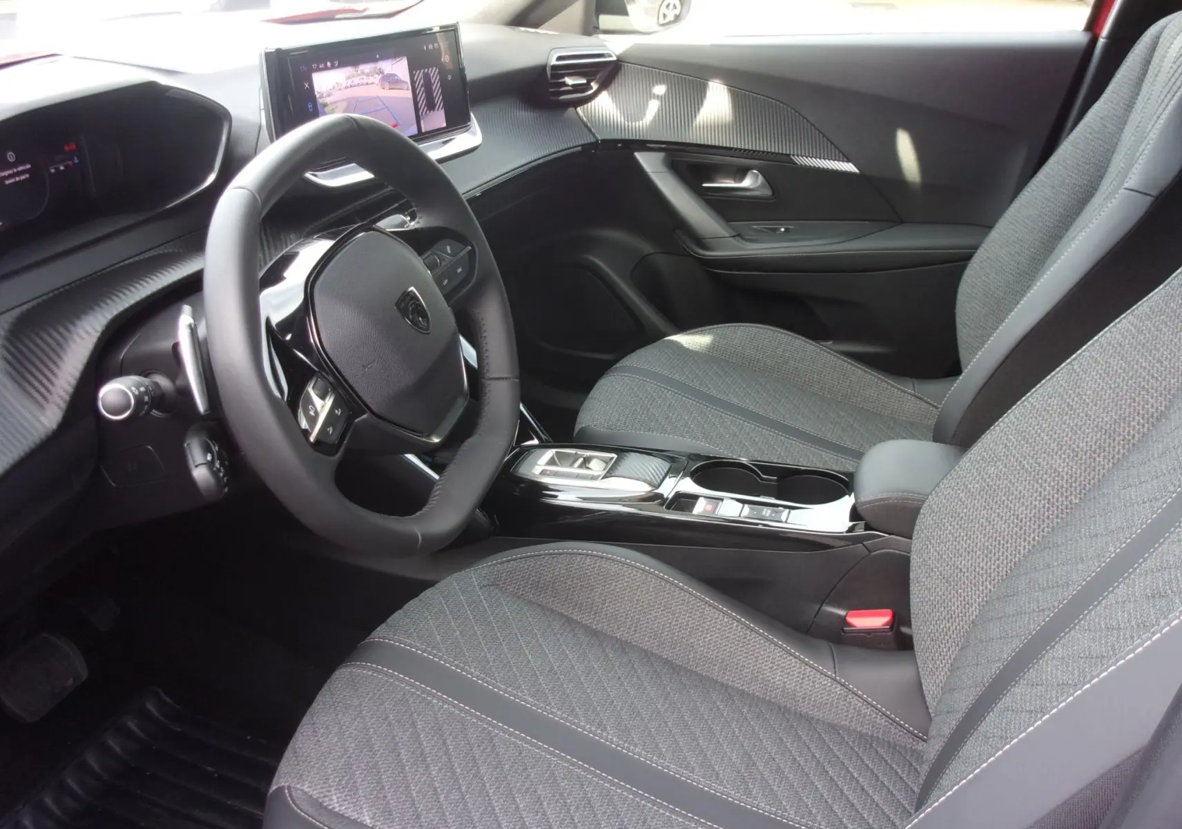 Vue intérieure côté conducteur du Peugeot 2008 2024, volant compact, sièges gris texturés et écran tactile affichant la caméra de recul.