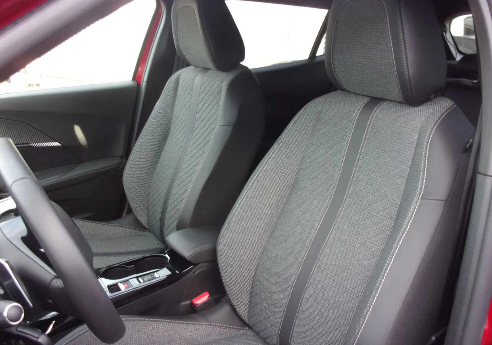Intérieur du Peugeot 2008 2024 en Rouge Elixir, vue côté gauche sur les sièges avant en tissu et cuir gris.