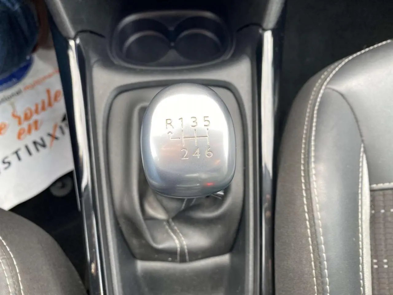 Gros plan sur le levier de vitesse manuel gris argenté du Peugeot 2008 2019, entouré de sièges noirs avec surpiqûres blanches.