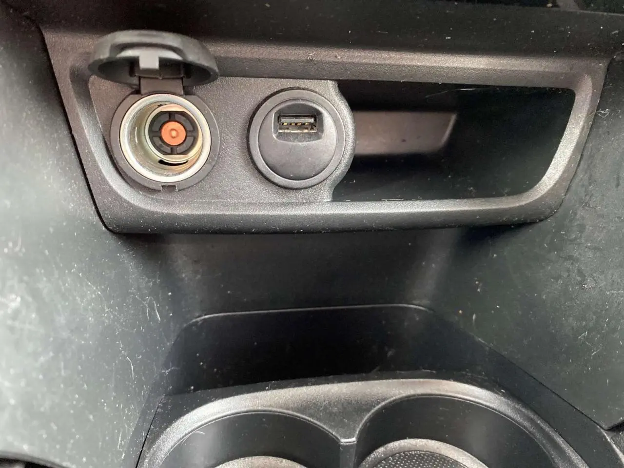 Gros plan sur la prise allume-cigare et port USB dans la console centrale noire du Peugeot 2008 gris platinium.