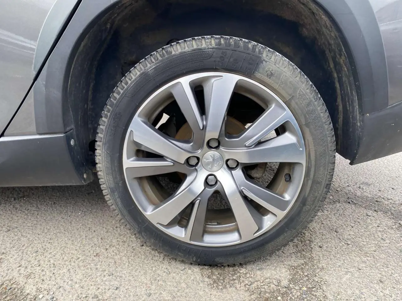 Gros plan sur la roue avant gauche du Peugeot 2008 gris platinium, mettant en valeur la jante alliage et le pneu.